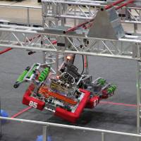 Two robots hang from a bar at the end of a match